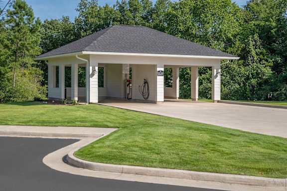 A white house with a black roof and a bicycle hanging on the wall.