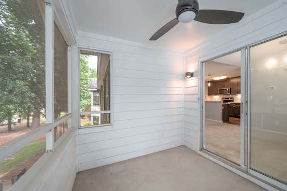 A room with a ceiling fan and sliding glass doors.