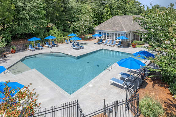 A pool surrounded by trees and a gazebo.