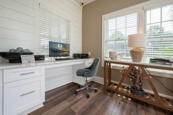 A home office with a desk, chair, and a window with blinds.