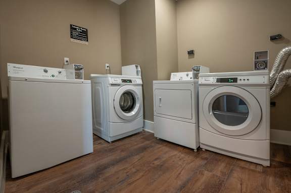 Three front load washing machines in a laundry room.