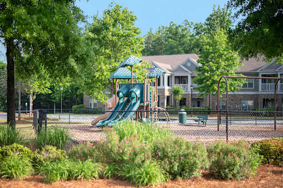 A playground with a green slide and a blue canopy.