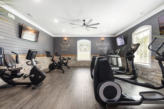 a gym with cardio machines and a tv