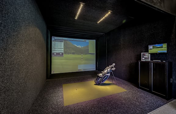 A motorcycle is displayed in a room with a large screen showing a virtual environment.