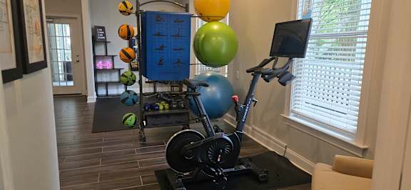 A blue and black exercise bike is in a room with a window.