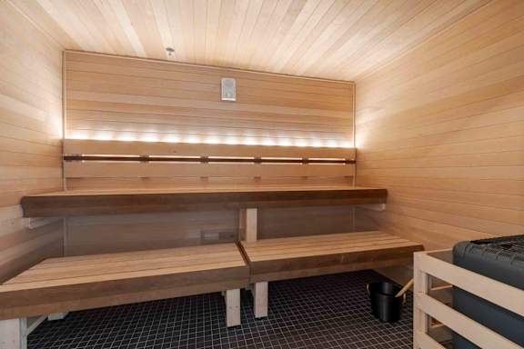 A wooden sauna with benches and lights on the wall.