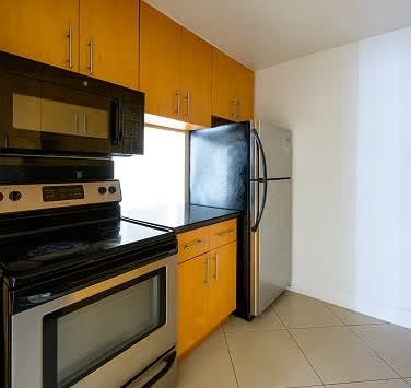 A kitchen with a black stove top oven and a black microwave above a black refrigerator.