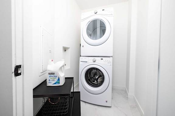 A white washing machine is in a small laundry room.