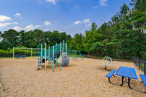 A playground with a blue table and a swing set.
