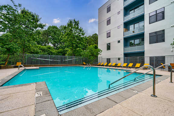 A swimming pool surrounded by a metal fence and yellow chairs.