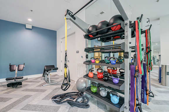 A gym with a variety of equipment including kettlebells, resistance bands, and a cable machine.
