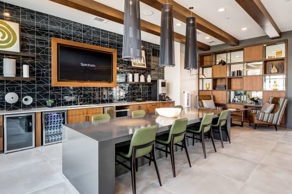 a kitchen with a long counter and chairs and a tv