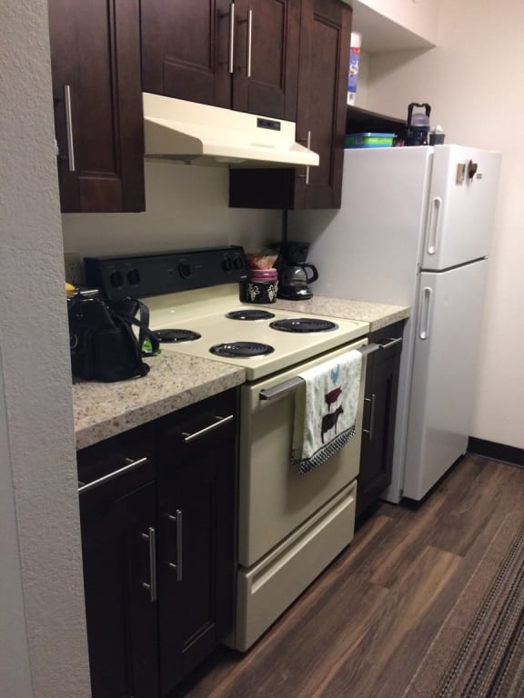 a kitchen with a white refrigerator freezer next to a stove top oven