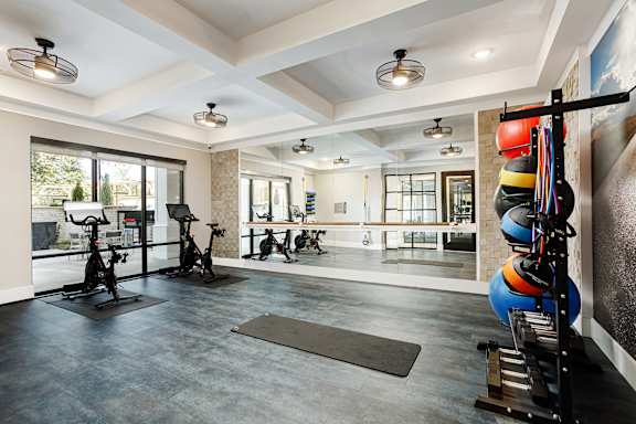 A spacious gym with exercise equipment and a mirrored wall.