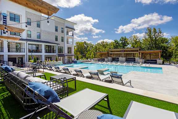 A large outdoor pool area with sun loungers and a building in the background.