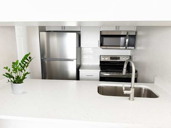 A kitchen with a stainless steel refrigerator, microwave, oven, and dishwasher.