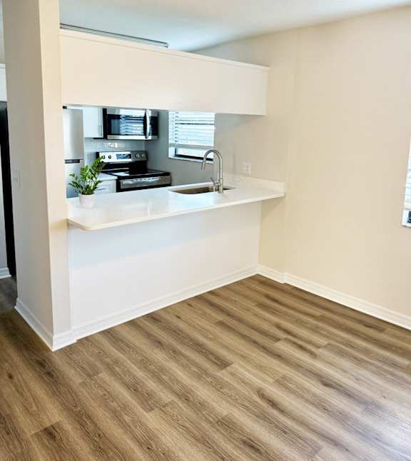 A kitchen with a white countertop and wooden flooring.