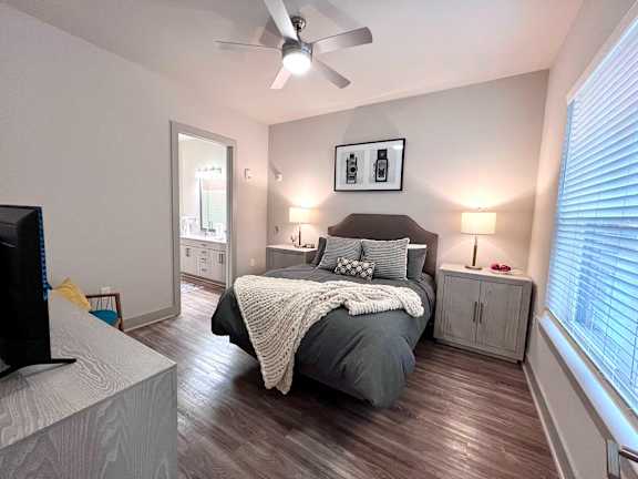 A bedroom with a bed, a television, and a ceiling fan.