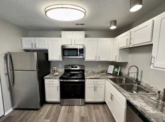 A kitchen with a refrigerator, oven, and microwave.