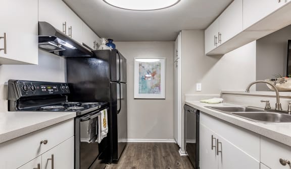 an apartment kitchen with black appliances and white cabinets at L'Estancia, Sarasota, 34231