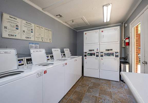 A laundromat with washers and dryers lined up.