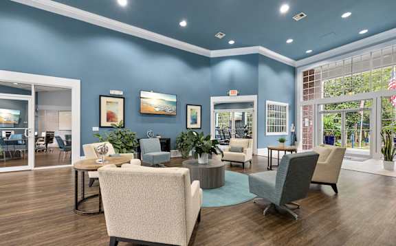 A room with blue walls and wooden floors has a large table surrounded by chairs.