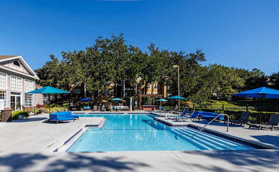 A large swimming pool surrounded by trees and lounge chairs.