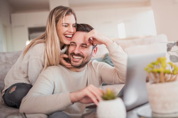 a man and a woman sitting on a couch looking at a laptop