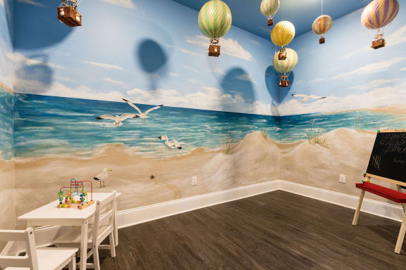 a childs playroom with a mural of a beach and hot air balloons