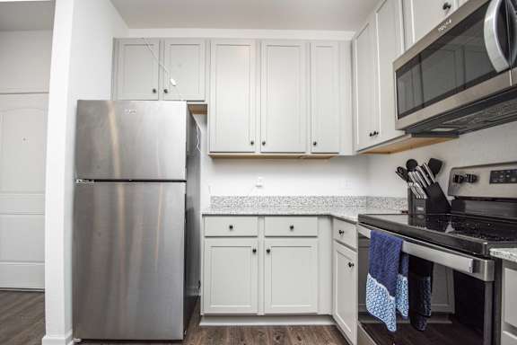 A kitchen with a stainless steel refrigerator and white cabinets.