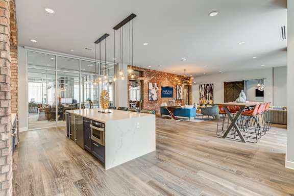 A modern kitchen with a wooden floor and a brick wall.