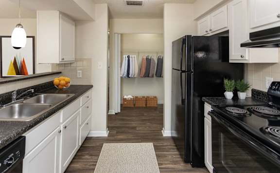 A kitchen with black appliances and white cabinets.