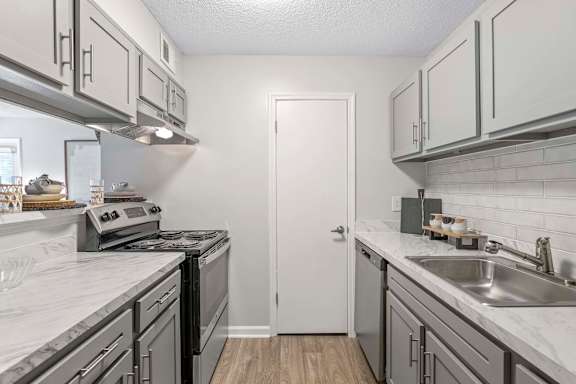 A kitchen with a white door and a stove top oven.