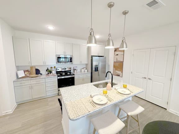 A kitchen with a table set for two with plates and glasses of orange juice.