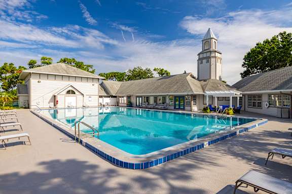 A large swimming pool in front of a building with a tower at Lake in the Woods, Florida, 32901