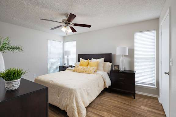 A bedroom with a bed, nightstand, and a plant at Lake in the Woods, Florida, 32901