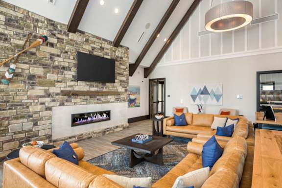 A living room with a stone fireplace and a flat screen TV mounted on the wall.