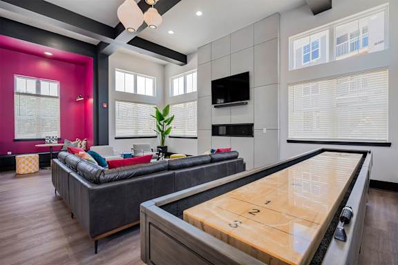 A room with a shiny wooden table and a couch.
