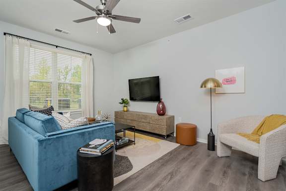 A living room with a blue couch, a television, a lamp, and a rug.
