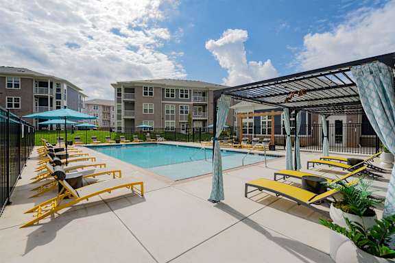 A pool area with sun loungers and umbrellas.
