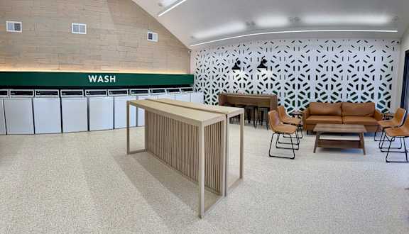 A room with a wash sign on the wall and a row of sinks.