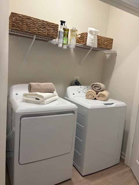 Two white front loading washing machines with towels on top.
