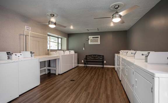 A laundry room with a washer and dryer on the left and a bench in the middle.