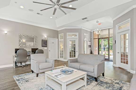 A living room with a white ceiling fan and grey couches.