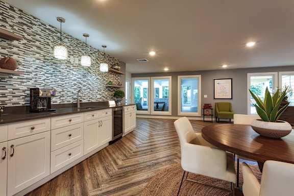 A modern kitchen with a stone wall and wooden floors.