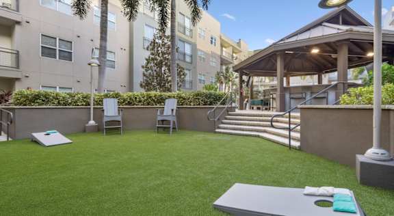 A backyard with a lawn, a table, chairs, and a gazebo.