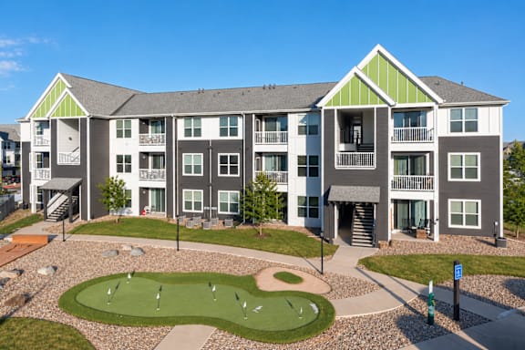 A large apartment complex with a green lawn and a putting green in front.