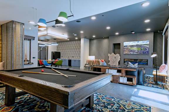 A pool table is in the middle of a room with a fireplace and a TV.