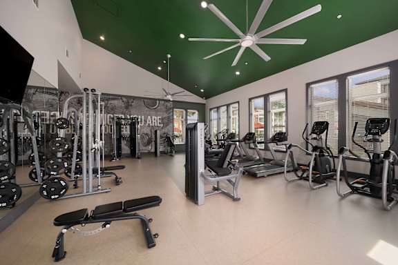 A gym with a variety of equipment including treadmills, weights, and exercise machines.