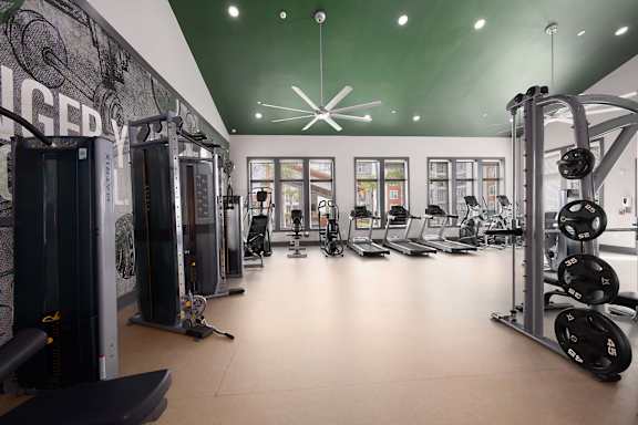 A gym with a variety of equipment including treadmills, weights, and exercise machines.